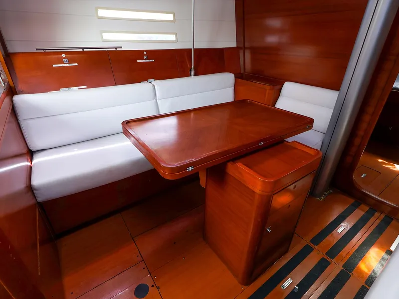 Slide: The Image of Interior of 2011 Dufour 40E Performance yacht with wooden table and white seating. - 32