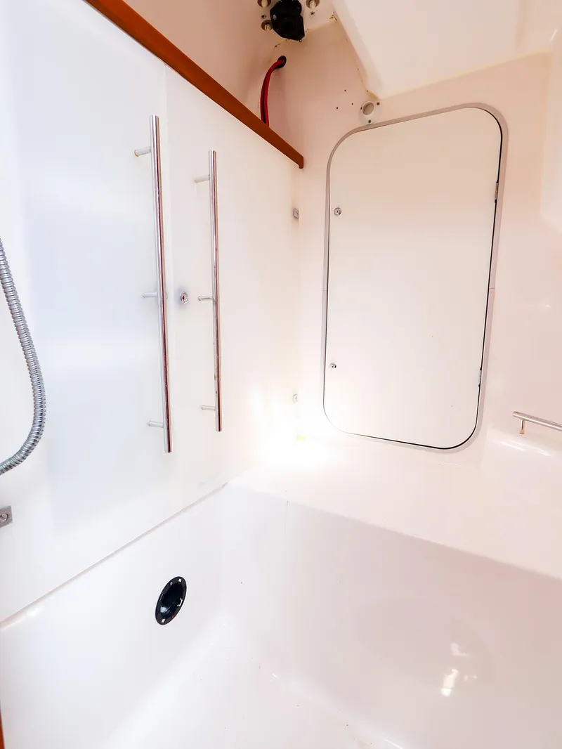 Slide: The Image of Interior of 2011 Dufour 40E Performance yacht, featuring sleek white surfaces and storage compartment. - 39