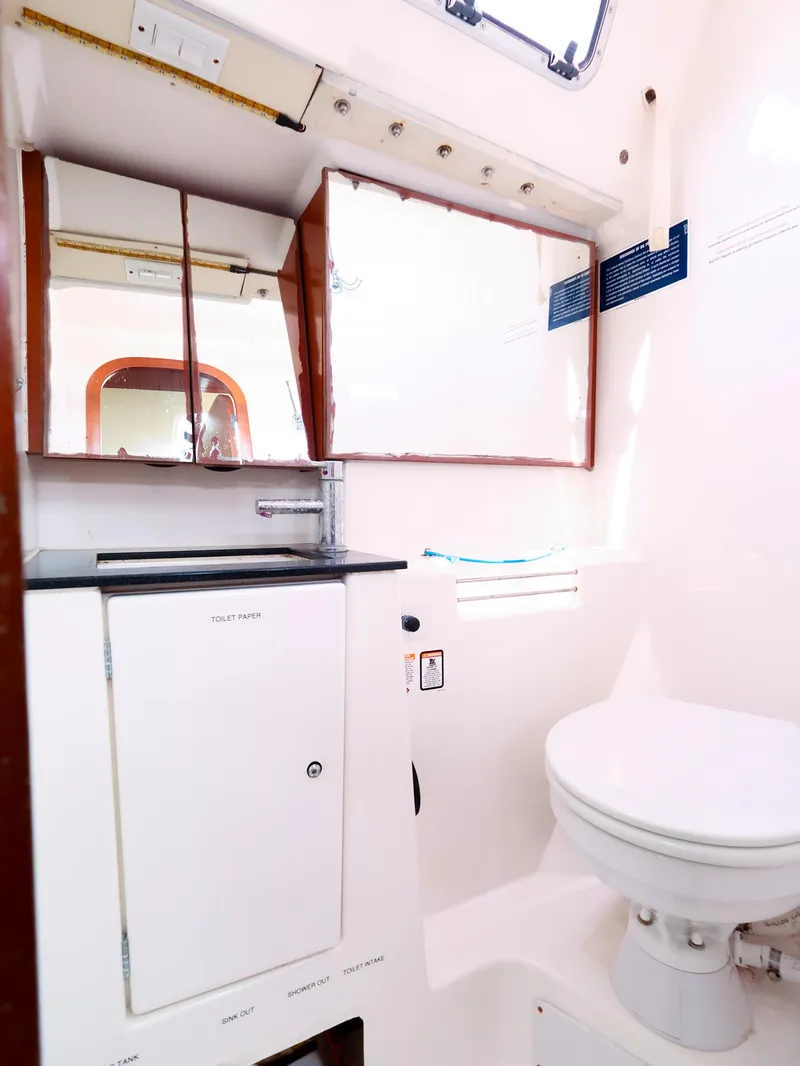 Slide: The Image of Bathroom interior of 2011 Dufour 40E Performance yacht, featuring toilet and mirrored cabinets. - 40