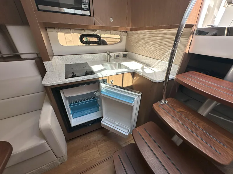 Slide: The Image of 2015 Sea Ray 350 Sundancer yacht kitchen with open fridge, stove, and wooden stairs. - 23
