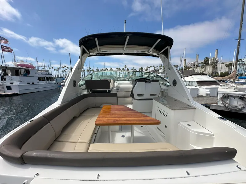 Slide: The Image of 2015 Sea Ray 350 Sundancer yacht interior with seating and table, docked at marina. - 9