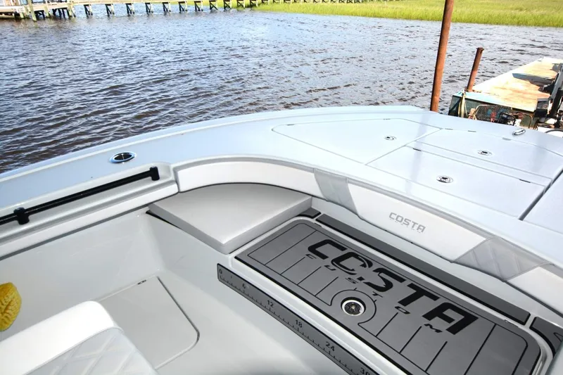 Slide: The Image of 2024 Costa Custom Boats 264HC interior, featuring sleek design and spacious seating by the water. - 11