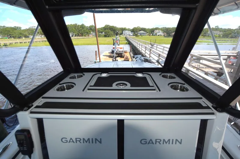 Slide: The Image of 2024 Costa Custom Boats 264HC interior with Garmin equipment, docked by a scenic waterfront. - 21