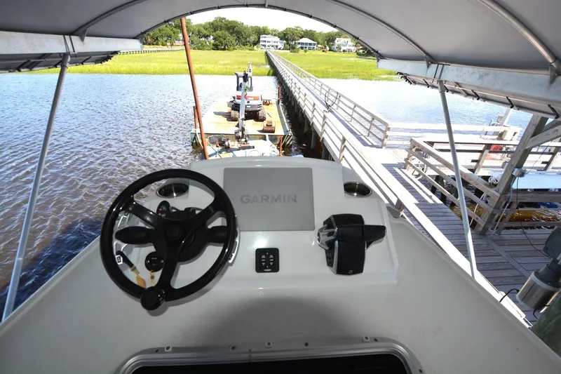 Slide: The Image of 2024 Costa Custom Boats 264HC helm with Garmin navigation, docked by a scenic waterfront. - 23