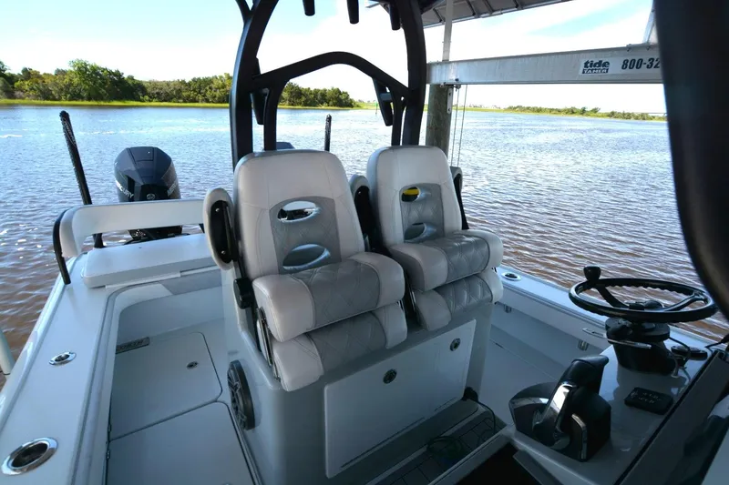 Slide: The Image of 2024 Costa Custom Boats 264HC helm with dual seats, steering wheel, and water view. - 26