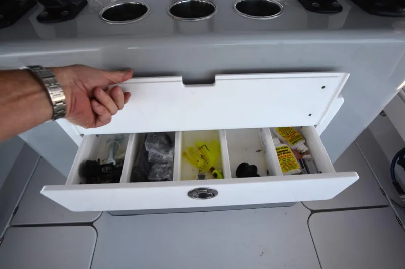 Slide: The Image of Open storage drawer on 2024 Costa Custom Boats 264HC, showing organized fishing gear and supplies. - 29