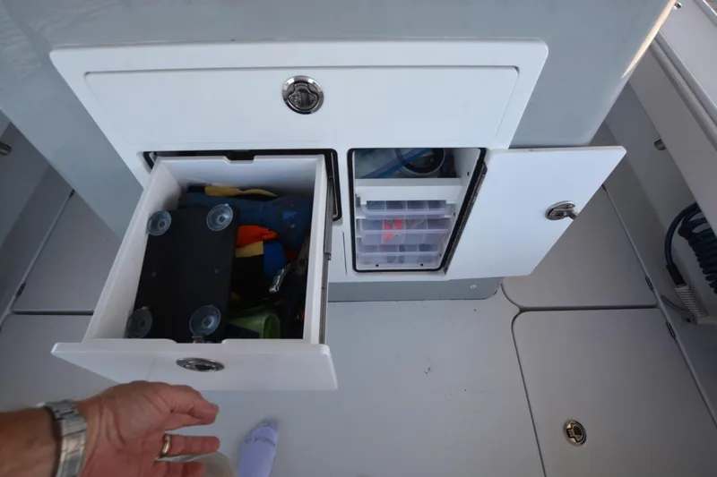 Slide: The Image of 2024 Costa Custom Boats 264HC storage compartments with open drawers and visible fishing gear. - 30