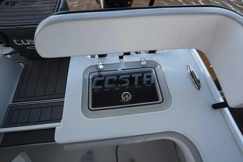 Slide: The Image of 2024 Costa Custom Boats 264HC interior detail with storage compartment and logo. - 33