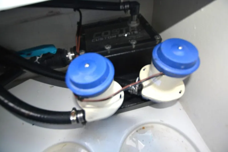 Slide: The Image of 2024 Costa Custom Boats 264HC engine compartment with blue-capped components and wiring. - 38