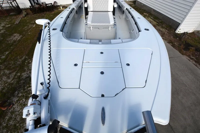 Slide: The Image of 2024 Costa Custom Boats 264HC, sleek white deck view with seating and storage compartments. - 5