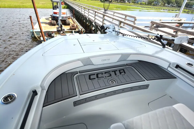 Slide: The Image of 2024 Costa Custom Boats 264HC on water near dock, showcasing deck and seating area. - 7