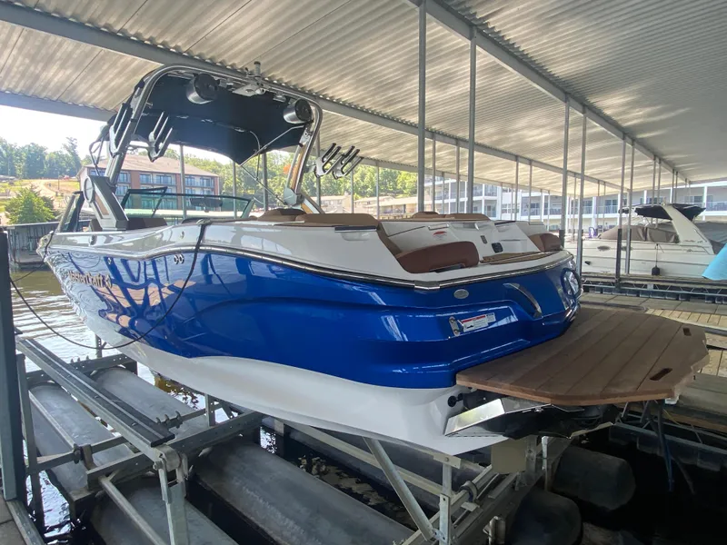 Slide: The Image of 2022 MasterCraft X26 boat in a marina, featuring a sleek blue and white design. - 10