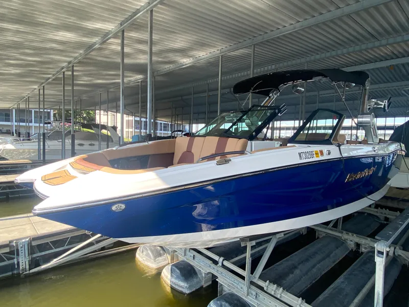 Slide: The Image of 2022 MasterCraft X26 boat in dock, featuring sleek blue and white design. - 11