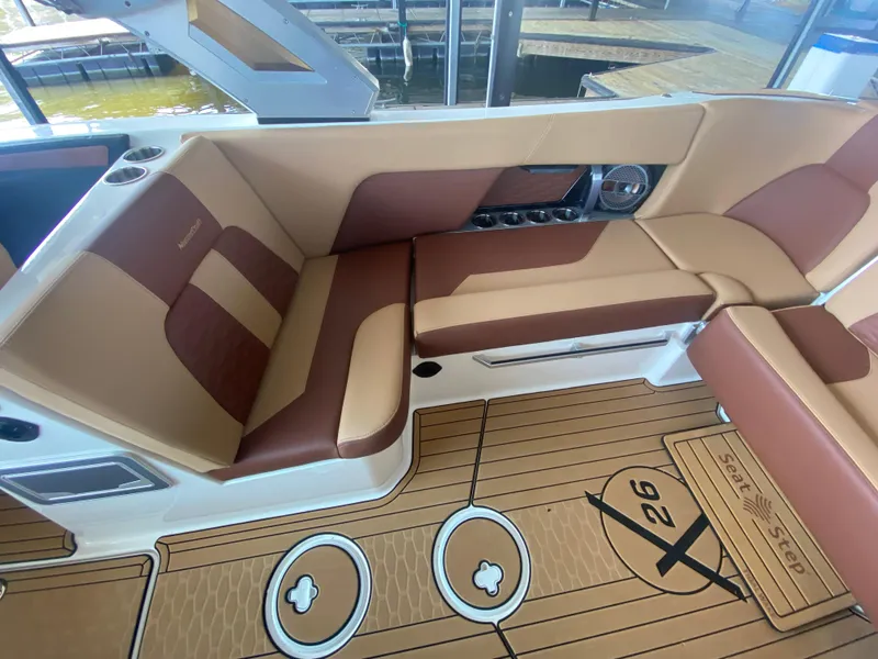 Slide: The Image of 2022 MasterCraft X26 boat interior with tan and brown seating, featuring cup holders and stylish flooring. - 21