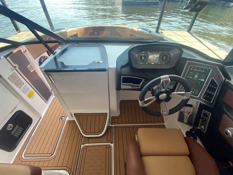 Slide: The Image of 2022 MasterCraft X26 boat cockpit with modern steering and digital dashboard, docked by the water. - 32