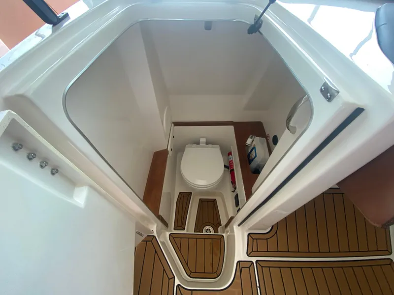 Slide: The Image of 2022 MasterCraft X26 boat interior with a compact bathroom and wooden flooring. - 33