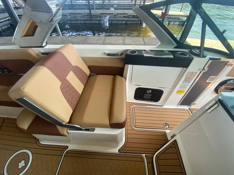 Slide: The Image of 2022 MasterCraft X26 boat interior with tan and brown seating, wood-style flooring. - 35
