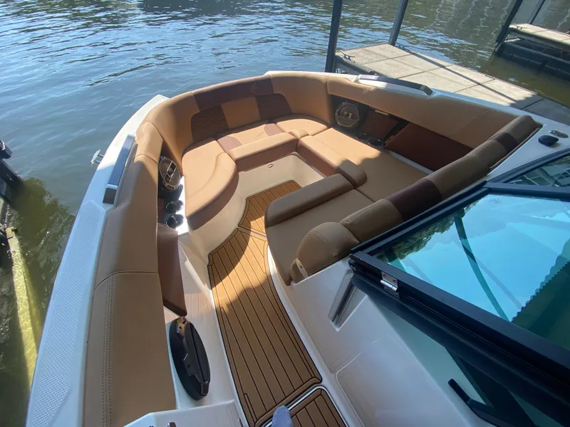 Slide: The Image of 2022 MasterCraft X26 boat interior with tan seating and wood flooring by the water. - 37