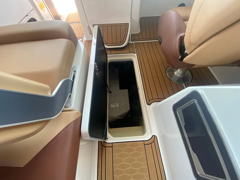 Slide: The Image of 2022 MasterCraft X26 boat interior with open storage compartment and tan seating. - 43