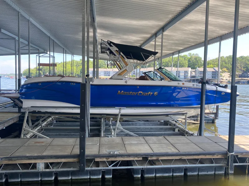 Slide: The Image of 2022 MasterCraft X26 boat docked under a covered marina on a sunny day. - 8