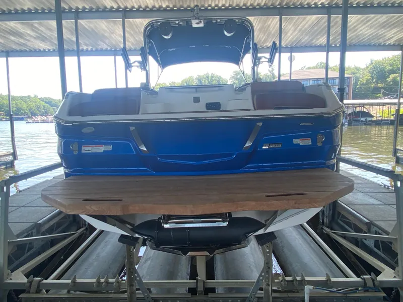 Slide: The Image of 2022 MasterCraft X26 boat in dock, rear view, blue exterior, wooden platform. - 9