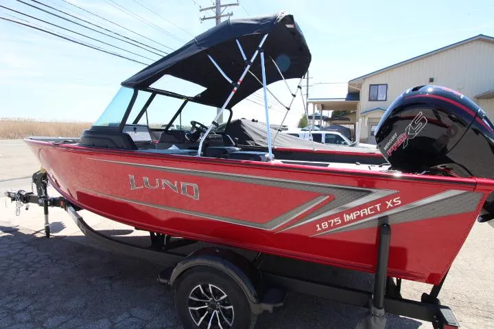 Slide: The Image of 2025 Lund 1875 Impact XS Sport boat in vibrant red, parked on a trailer. - 1