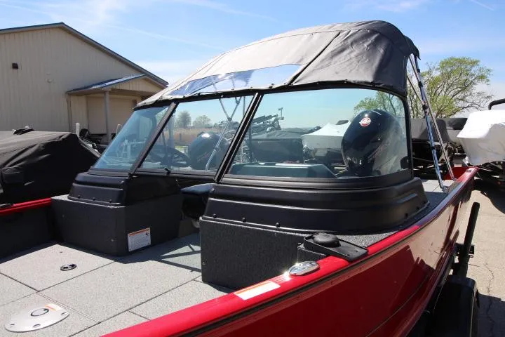 Slide: The Image of 2025 Lund 1875 Impact XS Sport boat with canopy, parked outdoors. - 12