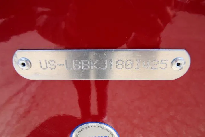 Slide: The Image of 2025 Lund 1875 Impact XS Sport boat identification plate on red surface. - 13