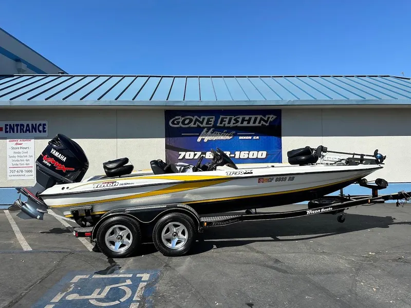 Slide: The Image of 2004 Triton Tr-20XDC boat with Yamaha engine on trailer, parked outside a marine store. - 1