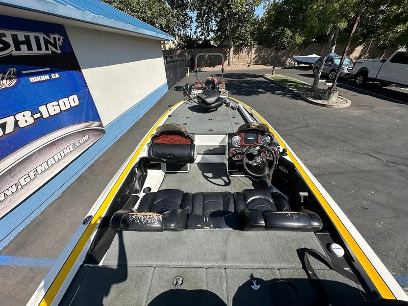 Slide: The Image of 2004 Triton Tr-20XDC boat interior with steering wheel and seating, parked outdoors. - 11