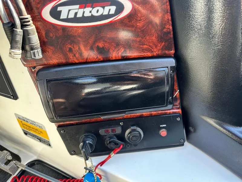 Slide: The Image of Control panel of a 2004 Triton Tr-20XDC boat with wood finish and logo. - 20