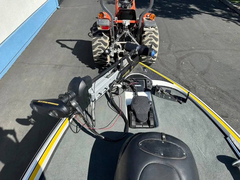 Slide: The Image of 2004 Triton Tr-20XDC boat with trolling motor, hitched to a tractor on a paved surface. - 24