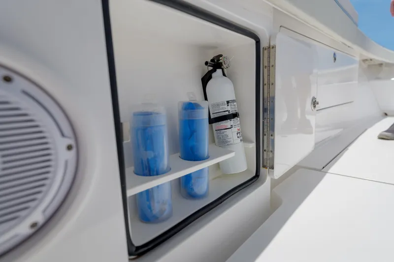 Slide: The Image of Open storage compartment on 2022 Valhalla Boatworks V41, featuring fire extinguisher and blue containers. - 37