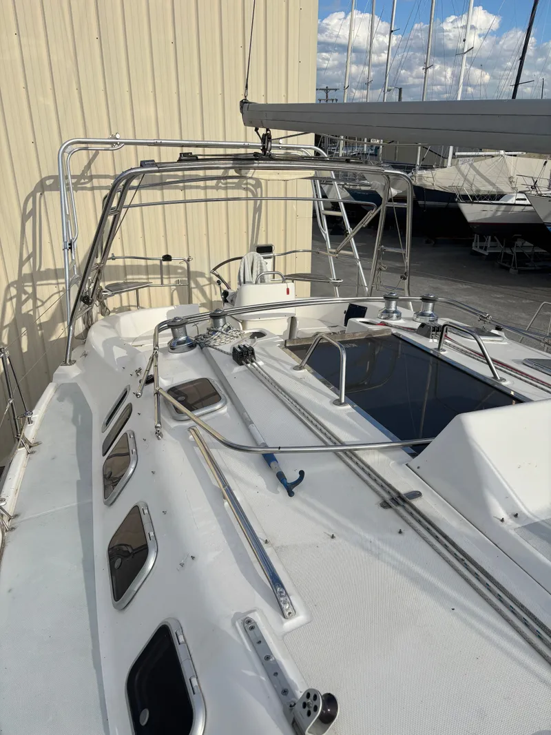 Slide: The Image of 2001 Hunter 460 sailboat deck with rigging and windows, docked near a beige building. - 16
