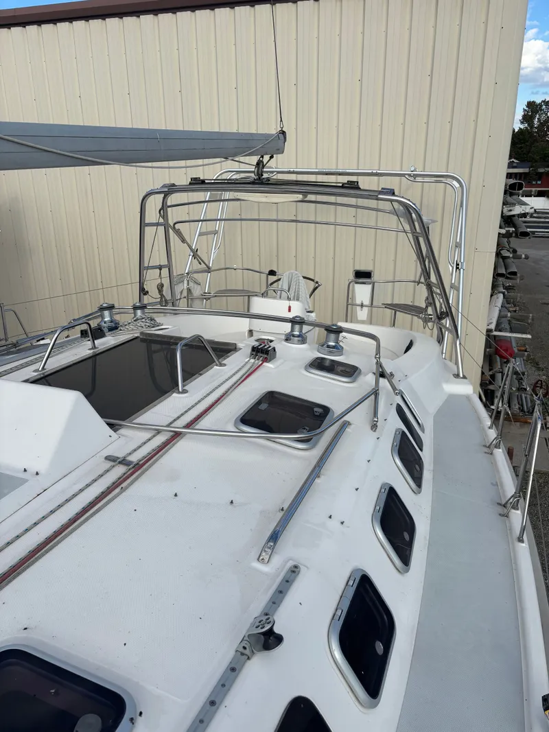 Slide: The Image of 2001 Hunter 460 sailboat deck with winches and hatches, docked near a beige building. - 24