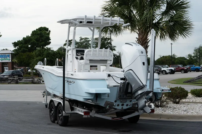 Slide: The Image of 2026 Caymas 24 HB boat on trailer, parked near palm tree. - 5