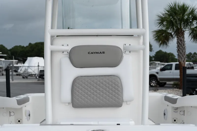 Slide: The Image of 2026 Caymas 24 HB boat interior with cushioned seating and console, parked outdoors. - 7