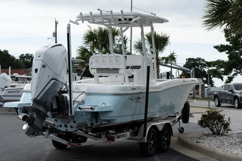 Slide: The Image of 2026 Caymas 24 HB boat on trailer, featuring powerful outboard motor, parked near palm trees. - 8