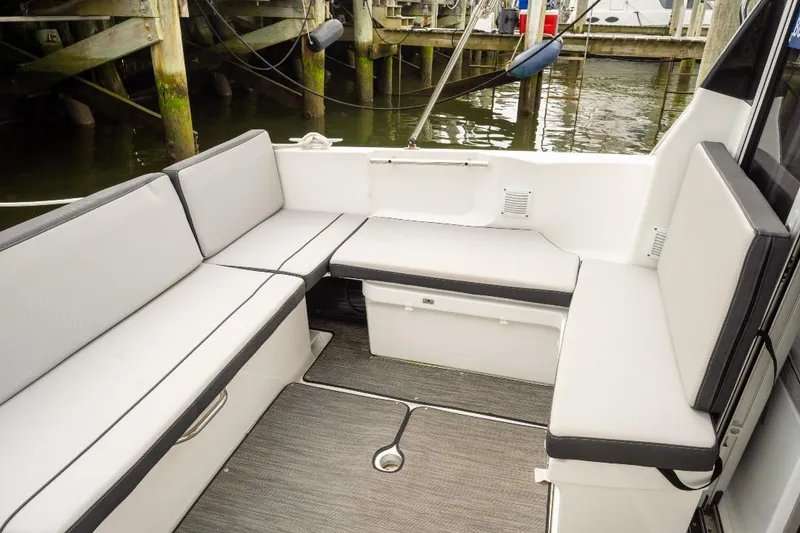 Slide: The Image of 2021 Jeanneau NC Weekender 795 Series 2 boat interior with cushioned seating and dock view. - 13