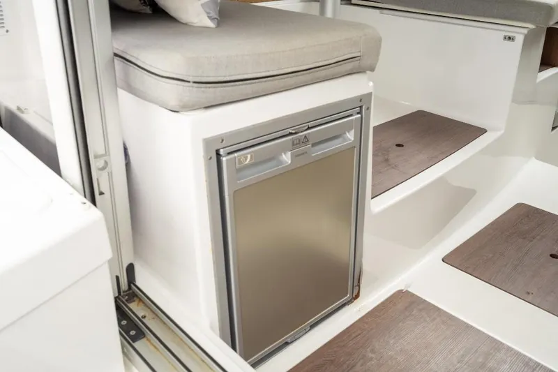 Slide: The Image of Interior of 2021 Jeanneau NC Weekender 795 Series 2, featuring compact fridge and seating. - 21