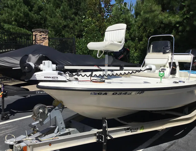 Slide: The Image of 2015 Mako 18 LTS boat with Minn Kota motor on trailer, surrounded by trees. - 2