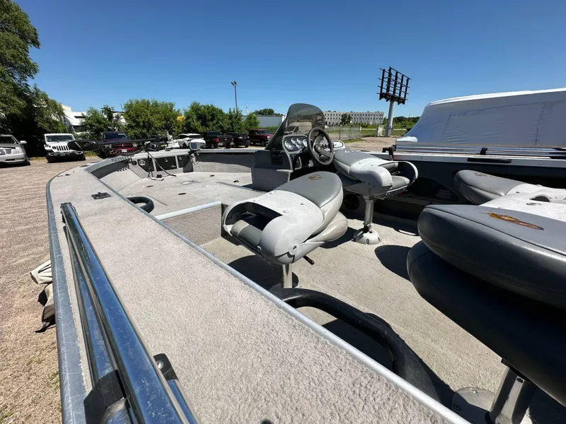 Slide: The Image of 2005 G3 1875 boat interior with seating and steering wheel, parked outdoors under clear sky. - 14
