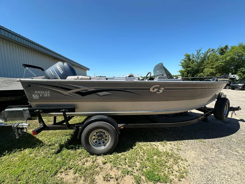 Slide: The Image of 2005 G3 1875 Angler V185 boat on trailer, parked outdoors under clear blue sky. - 5
