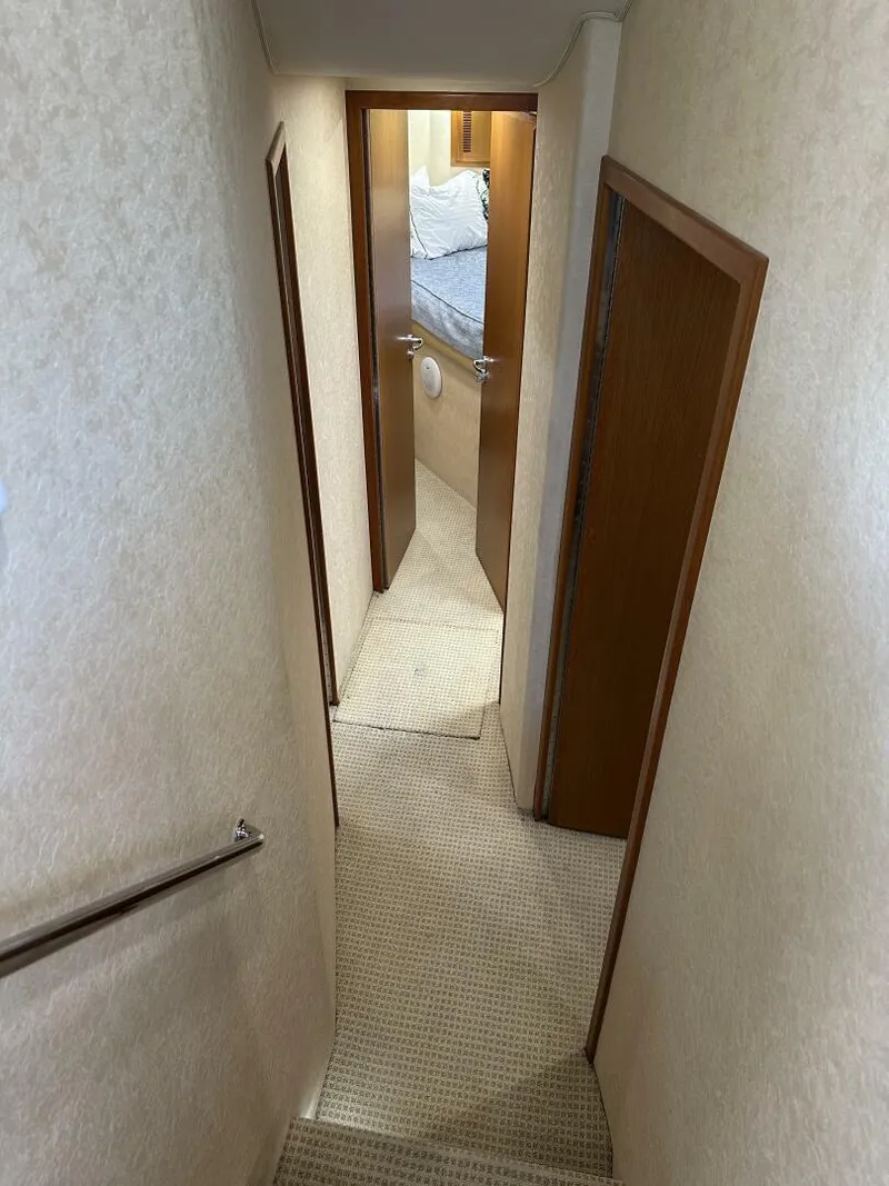 Slide: The Image of Narrow hallway inside 2006 Cabo 48 Convertible yacht, leading to a cozy bedroom. - 11