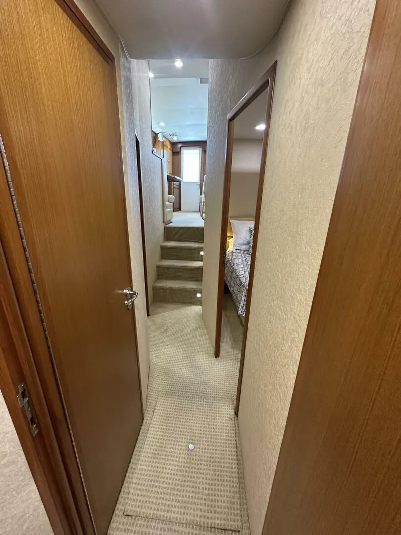 Slide: The Image of Interior hallway of a 2006 Cabo 48 Convertible yacht with carpeted flooring and wooden doors. - 17