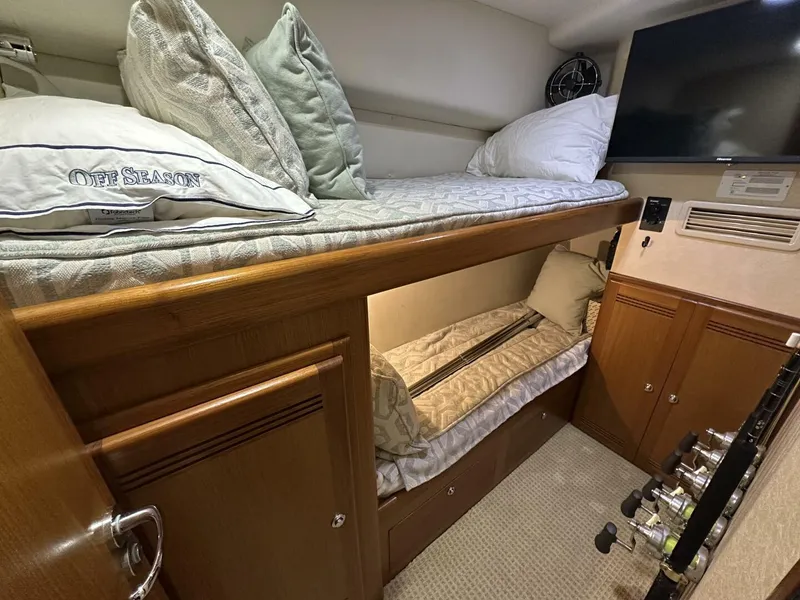 Slide: The Image of 2006 Cabo 48 Convertible yacht cabin with bunk beds, pillows, and fishing rods. - 19