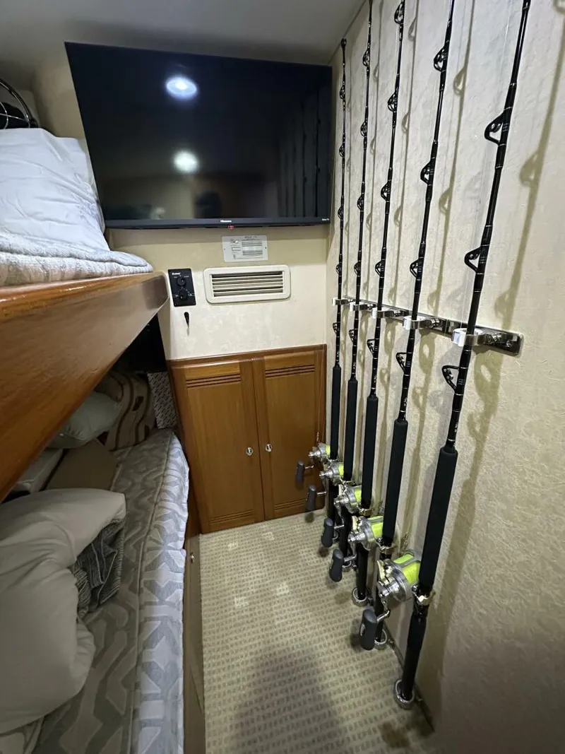 Slide: The Image of Interior of 2006 Cabo 48 Convertible with fishing rods, bunk beds, and TV. - 23