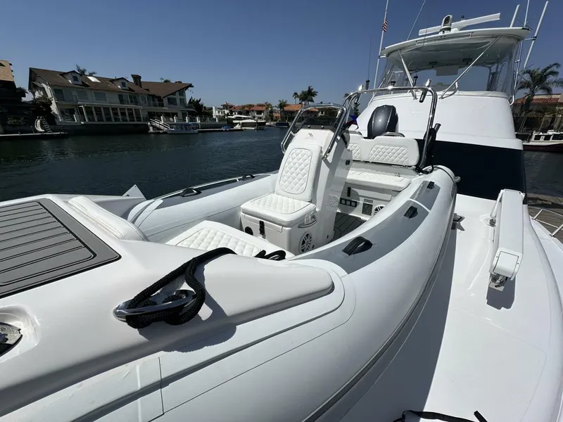 Slide: The Image of 2006 Cabo 48 Convertible yacht with luxurious seating, docked in a scenic waterfront area. - 29