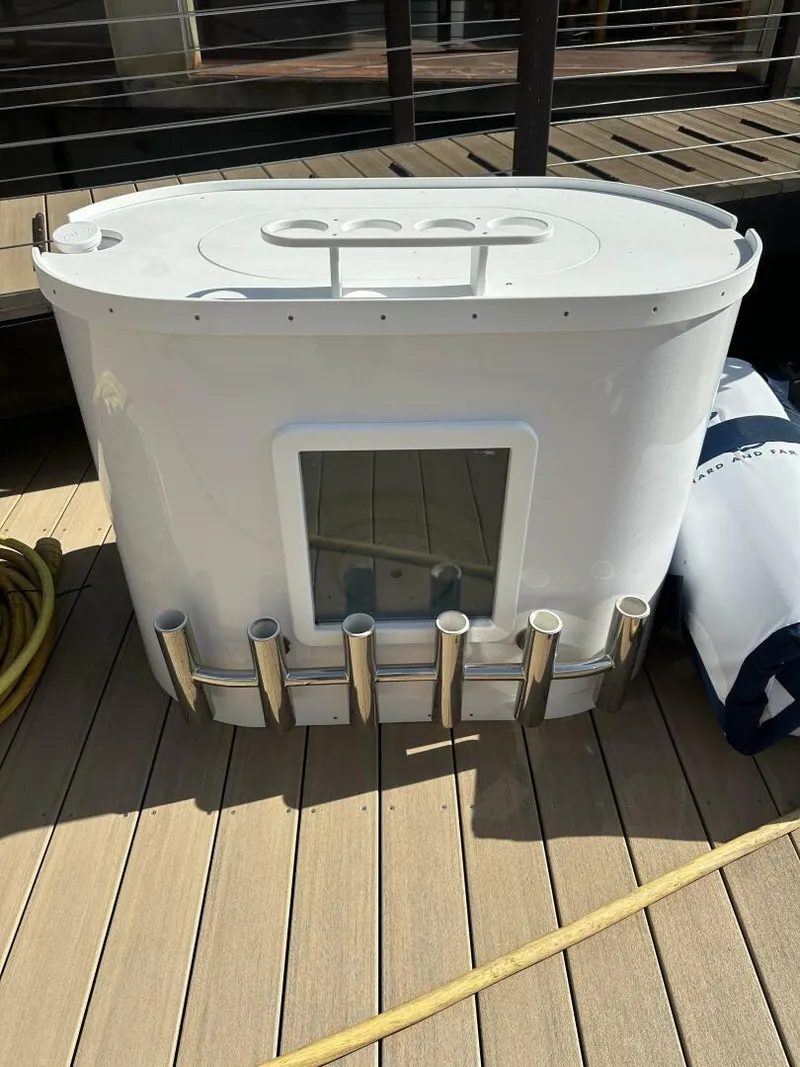 Slide: The Image of 2006 Cabo 48 Convertible boat accessory on wooden deck, featuring rod holders and storage compartment. - 48