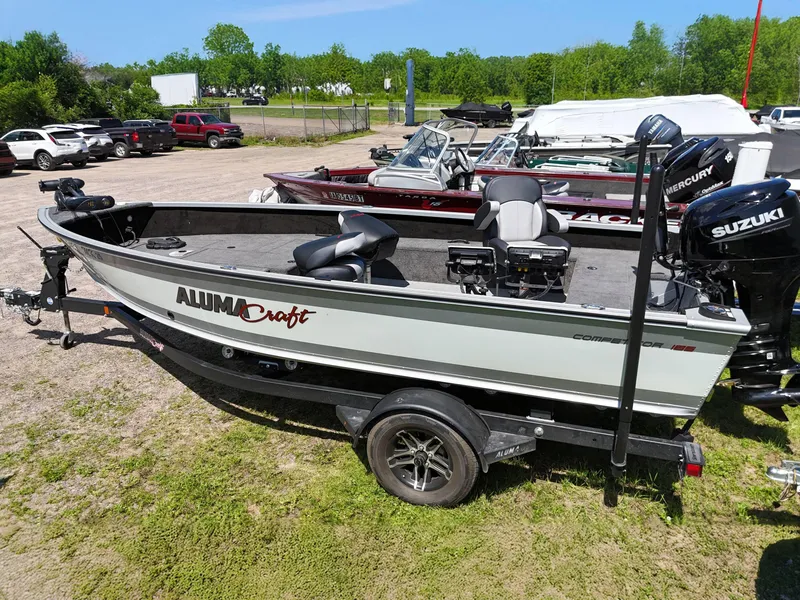 Slide: The Image of 2023 Alumacraft Competitor 185 Tiller boat on trailer, parked outdoors. - 10